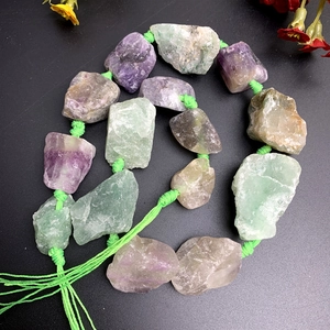 Macro detail of raw purple and green fluorite crystal strand with handmade knots
