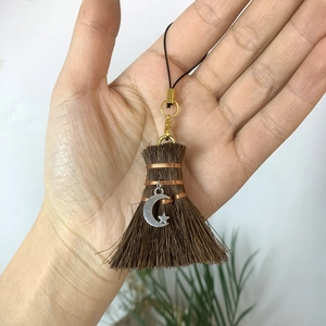 Detailed view of handmade mini broom pendant with silver star moon charm and copper wire