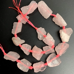 Detailed close-up of natural raw rose quartz beads with organic texture and pink cotton cord