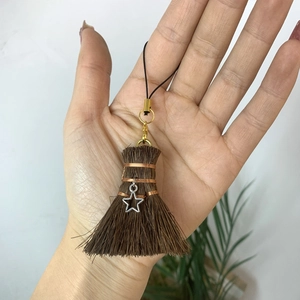 Detail of creative mini broom charm with fiber bristles and silver star pendant