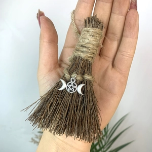 Detail of a handmade mini witch broom with a silver triple moon pentagram charm