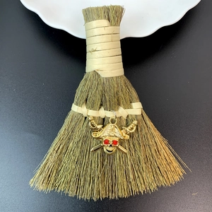 Detail of mini straw broom with gold pirate skull charm and red rhinestone eyes