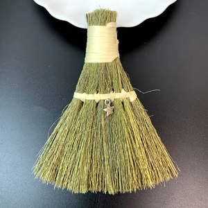 Close-up of handmade straw decorative broom with yellow ribbon and silver star charm