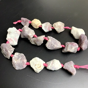 Macro shot of natural raw tourmaline stone beads in pink and white on a silk cord