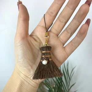 Detail of mini handmade broom charm with pearl accent and golden lobster clasp