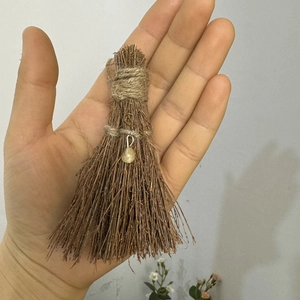 Detail shot of mini handmade broom charm with natural branches and yellow stone pendant