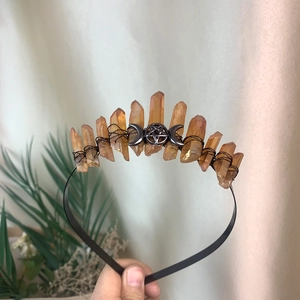 Detail of handmade orange crystal crown with silver triple moon and pentagram badge