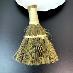 Close-up of Halloween mini straw broom featuring a vintage bronze skeleton hand charm