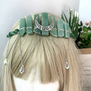 Detail of green crystal crown featuring silver wire wrap, moon charm, and hanging chain tassels