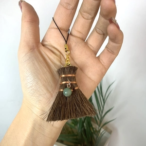 Detail of handmade ethnic broom pendant with natural fiber, copper wire and green bead