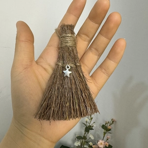 Close-up of mini wooden wizard broom pendant with silver star charm and hemp rope detail