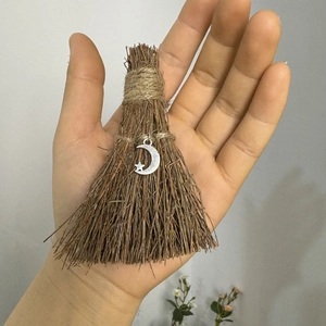 Macro view of handmade wizard broom pendant with silver moon charm and natural wood texture