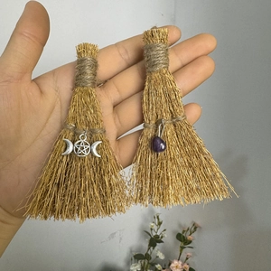 Detail of mini handmade straw brooms with pentagram charm and purple crystal stone