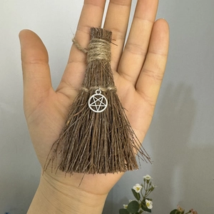 Close-up of handmade mini witch broom with twine wrap and silver pentagram pendant