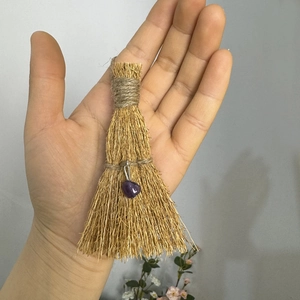Handmade decorative natural straw broom with purple heart crystal held by hand