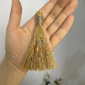 Close-up of handmade mini straw witch broom with amber bead for holiday decor