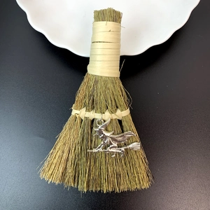 Handcrafted decorative straw broom with silver witch pendant for Halloween festive display