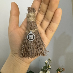 Detailed macro view of a handmade mini wizard broom pendant with a silver sun charm charm