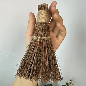Close-up of handmade mini decorative straw broom with hemp rope and red bead detail