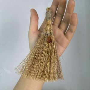 Detail of a handmade mini wicca witch broom with straw texture and gemstone pendant