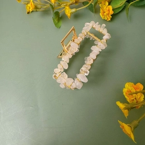 Détail d'une pince à cheveux dorée avec pierres naturelles roses et fil métallique