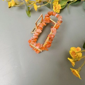 Vue détaillée du gravier de cristal orange incrusté sur une pince à cheveux dorée rectangulaire