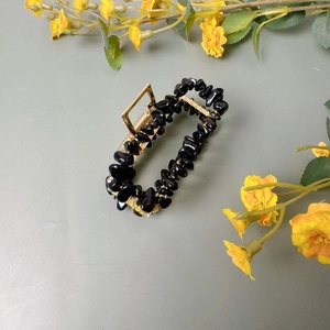 Détail d'une pince à cheveux papillon faite main avec cristaux noirs et finition dorée
