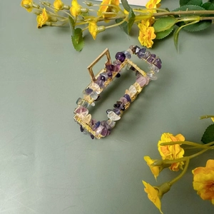 Détail macro d'une pince à cheveux en alliage doré avec cristaux violets et jaunes