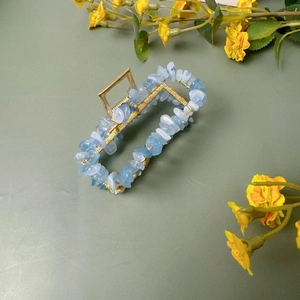 Détail d'une grande pince à cheveux dorée ornée de fragments de pierres de cristal bleu