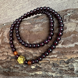 Double-layer garnet and red agate beaded bracelet with gold flower charm on bark