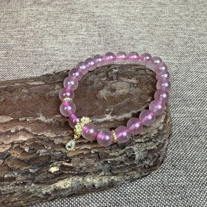 Bracelet en quartz fraise naturel 8mm avec détails en or 18k sur un socle en bois