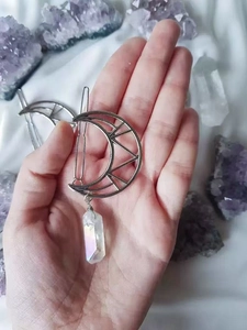 Close-up of a silver moon hair clip with iridescent crystal pendant held by hand