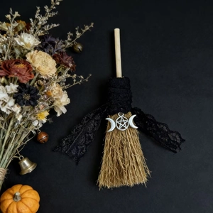 Detail of lace ribbon and silver triple moon goddess charm on decorative witch broom