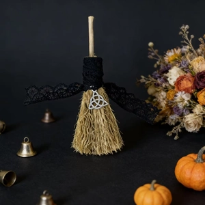 Detail of Halloween decorative broom with black lace bow and silver triquetra pendant