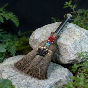 Detailed macro view of a handmade witch broom with crystal beads and bat charm on a rock