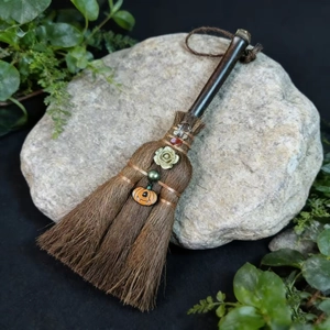 Detail of witch broom with green flower and pumpkin head on stone with green leaves