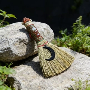 Macro view of handmade straw witch broom with natural crystals and crescent moon charm