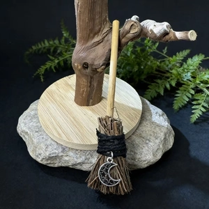 Macro detail of a handmade mini witch broom with wooden handle and silver moon pendant