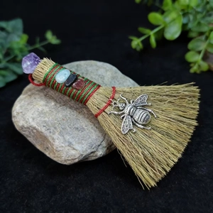 Macro detail of witch broom with amethyst crystal and vintage bee pendant decoration