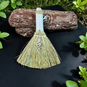 Detail of handcrafted straw besom broom with silver snake pendant on wood bark