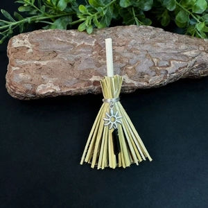 Detailed close-up of handmade witch broom with crystal and sun pendant on bark