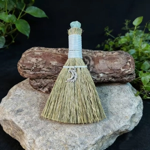 Macro detail of witch broom with crystal gemstone and moon pendant for altar decor