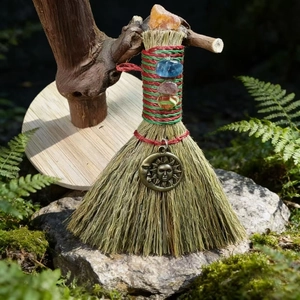 Detailed close-up of handmade witch broom with crystals and sun moon metal pendant