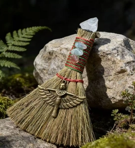 Detail of a handmade witch broom with white crystal cluster and brass winged goddess charm