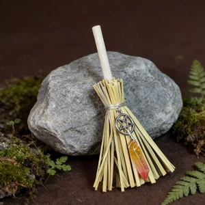 Detail shot of mini witch broom with crystal stone and pentagram charm on moss