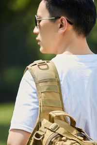 Close-up of padded shoulder strap on khaki tactical backpack with MOLLE webbing