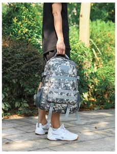 Detail of digital camouflage tactical backpack featuring MOLLE webbing and mesh side pocket