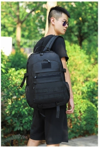 Detail view of black tactical backpack with MOLLE webbing and multi-layer zipper pockets