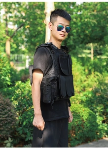 Side view of a black tactical vest with Molle system and utility pockets in outdoor setting