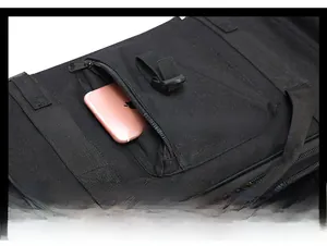 Detail of the middle zipper pocket on a black canvas tactical bag holding a mobile phone